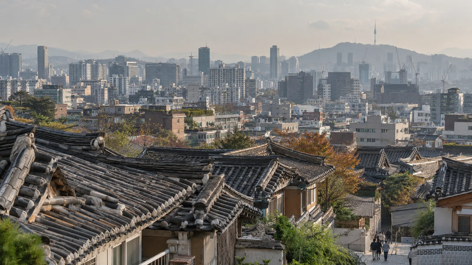 Old hanok roofs in the foreground with Seoul's apartment blocks, towers and Namsan behind